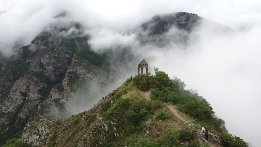 Aerial Drone view of Small chapel in the top of the mountain, surrounded by fog and clouds. Highland old building in Armenia, Caucasus Royalty-Free Stock Footage #1055402069