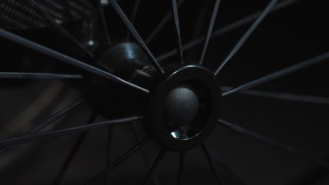 Close up spinning spokes and wheel hub of black wheelchair. Motion control system. Camera moving up