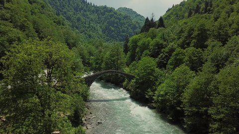 The city of Rize in Turkey.Sunny weather and great valley.An old stone bridge and a powerful river.The drone camera is approaching the bridge.