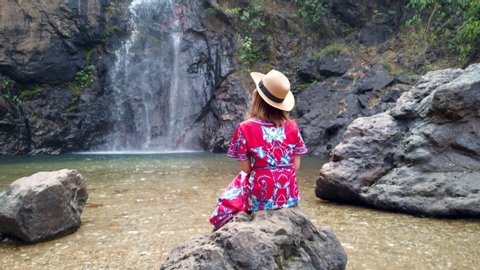 Eco travel nature background. Asian woman in a colorful dress enjoying deep forest famous Jokkadin Waterfall in Thong Pha Phum town national park located in Kanchanaburi Thailand
