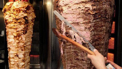 Shawarma meat being cut before making traditional Turkish Doner Kebab. Chef cutting the kebab meat with the sharp knife in street food restaurant in Istanbul, Turkey