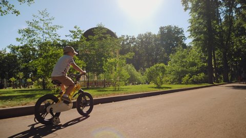 A child rides a bicycle in a city park. Happy boy riding bike, having fun outdoors on nature. Active sport family leisure.