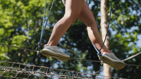 A teenage girl overcomes obstacles between trees at a height. Close up only legs