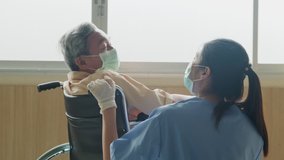 Asian nurse taking care of mature male patient sitting on wheelchair in hospital. Young woman and old man wearing surgical face mask for protection of covid 19 pandemic. Girl smile to elderly man. - Powered by Shutterstock - Get 15% off with code: PIKWIZARD15