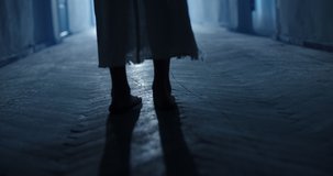Low angle shot of legs of little girl ghost slowly creeping on floor of hallway of old abandoned haunted house - horror scene, horror movie 4k footage