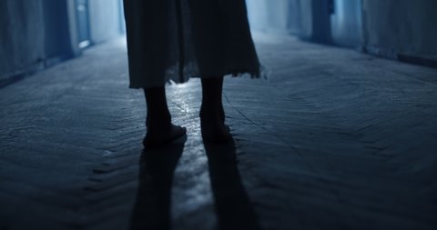 Low angle shot of legs of little girl ghost slowly creeping on floor of hallway of old abandoned haunted house - horror scene, horror movie 4k footage