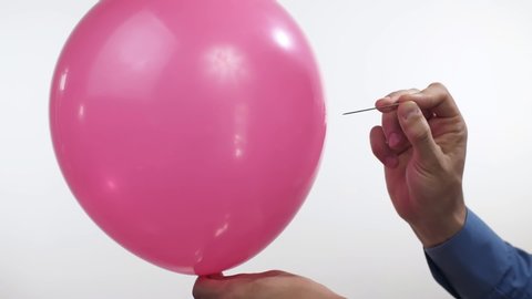 Man pierces a balloon with a needle