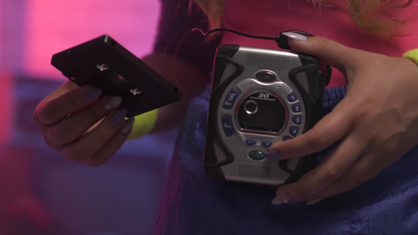 Closeup on a girl using a vintage portable cassette tape player by inserting a tape and pressing the play button to listen to her music in the 1980 1990 Royalty-Free Stock Footage #1055412350