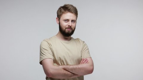 Handsome cheerful bearded guy looking at camera, smiling playfully and winking flirting, cheering up with optimistic tricky expression as if having idea. indoor studio shot isolated on gray background