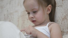 Child plays in the smartphone in the room. Distance learning of preschoolers online.