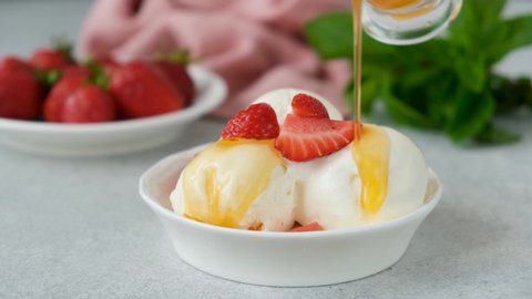 Lemon syrup pouring on vanilla ice cream scoops. Tasty summer dessert ice cream