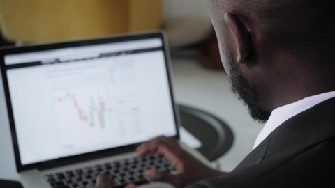 Black Businessman using laptop for analyzing data stock market, forex trading graph, stock exchange trading online, financial investment concept. close up