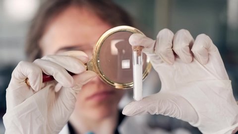 closeup portrait scientist doctor woman looking at test tube magnifier