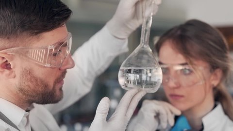Closeup portrait of woman and man scientist examining liquid in test tube