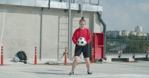 Teenager girl football soccer player practicing tricks, kicks and moves with ball on rooftop empty parking garage. Urban city lifestyle outdoors concepte. 4K UHD slow motion RAW graded footage