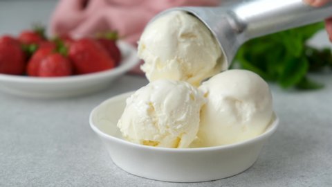 Vanilla ice cream with syrup. Lemon syrup pouring on vanilla ice cream scoops. Serving summer dessert ice cream in bowl
