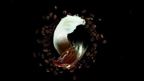 Super slow motion of rotating coffee beans with splashes on black background. Filmed on high speed cinema camera, 1000 fps.