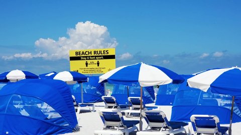 A prominent yellow sign illustrating the Beach Rules of social distancing to stay six feet apart. Clearwater Beach, FLorida, USA.