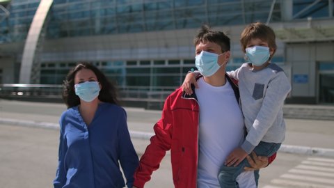 Happy family tourists mother, father, son little boy child in airport in protective medical face mask. Safe travel tourism kid. Virus outbreak Coronavirus COVID-19 flu quarantine pandemic. slow-mo 4 K