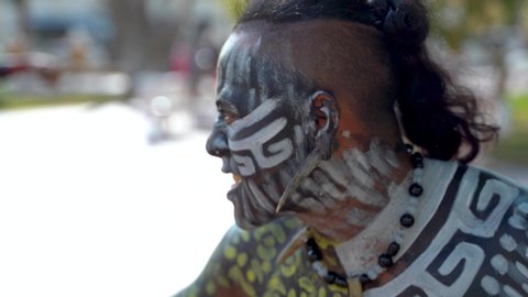 Extreme closeup portrait of Mayan or Aztec dancer with painted face performing for the camera.