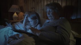 Grandfather and grandmother and granddaughter use gadgets before going to bed. The use of modern technology by different generations of people