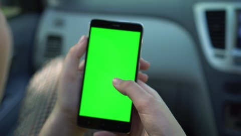 Close up of a woman's hand holding a mobile telephone with a vertical green screen in car chroma key smartphone technology cell phone street touch message display hand