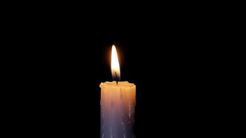A single white candle burning.Isolated candle burning with dark background. White paraffin candle with yellow shades burns on a black background. 
