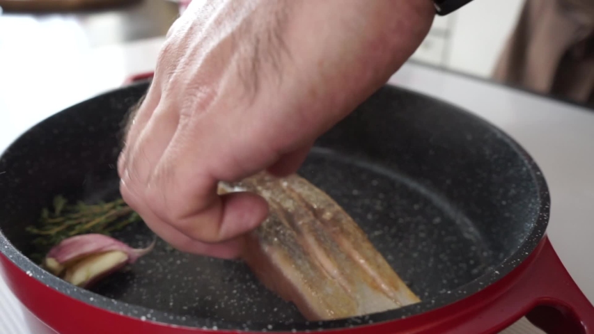 
fried fish and vegetables in a red pan