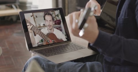 Online education, man learning guitar lesson during video call with tutor from home