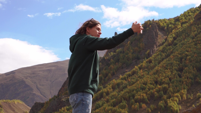 a girl photographs herself against the background of mountains