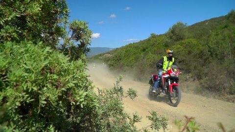 Motorcyclists ride fast on serpentines on a broken mountain road. POV Friends ride. Riding on a dusty mountain landscape road. A group of bikers. Enduro lifestyle. Africa twin.