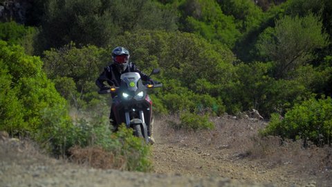 Motorcyclists ride fast on serpentines on a broken mountain road. POV Friends ride. Riding on a dusty mountain landscape road. A group of bikers. Enduro lifestyle. Africa twin.