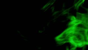 Green coloured smoke moving on black background.