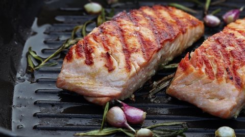 Grilled salmon fillets on a grill plate sprinkled with salt flakes