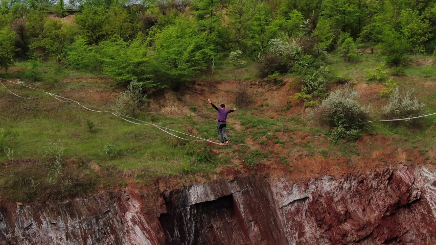 Aerial view on a man slacklining over a massive pit, scary height, 4k