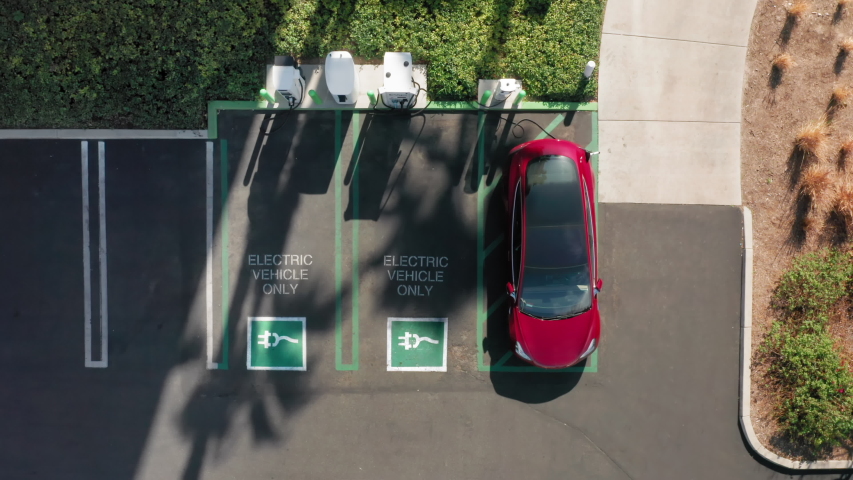 4K aerial overhead view on white electric vehicle parking at the charging station. Slow motion footage with environmental and eco-friendly, zero pollution technology concept design like Tesla vehicle Royalty-Free Stock Footage #1055446742