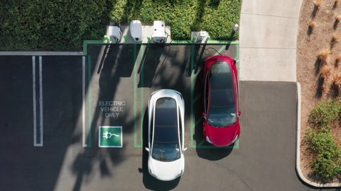 4K aerial overhead view on white electric vehicle parking at the charging station. Slow motion footage with environmental and eco-friendly, zero pollution technology concept design like Tesla vehicle