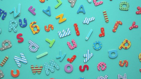 Colorful magnetic, plastic and paper alphabet letters placed randomly on blue background. Top view, flat lay.