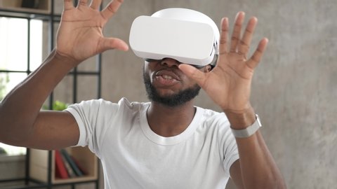 Handsome african american man wearing virtual reality headset. Augmented Reality. Man touch something using modern 3D vr glasses indoors. Student playing using VR glasses on a sunny day. Close up 4K स्टॉक वीडियो
