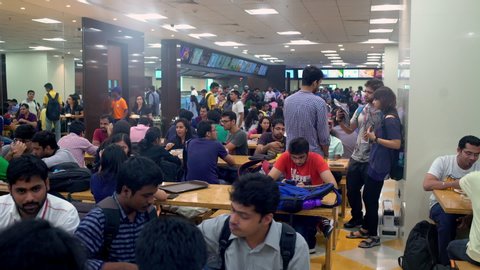 Multicultural students having fun, eating lunch in the International university cafeteria or campus. Friends discussing their studies during lunch break. Mumbai, Maharastra State, India - 2019