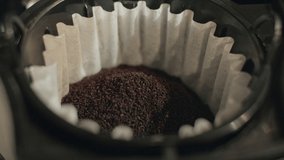 Close up of hand adds milled ground coffee in coffee filter for fresh dark coffee