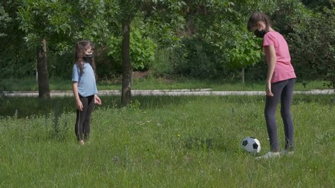Play soccer during epidemic. A children in medical mask play soccer on the park. A concept of sport during quarantine.