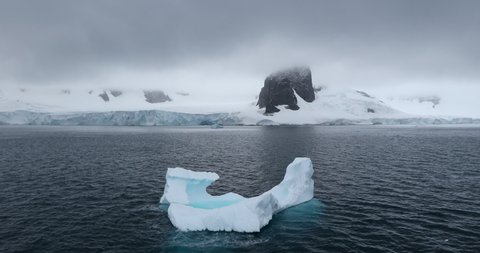 WS Iceberg and snow covered coast of Cuverville Island on cloudy day / Antarctica