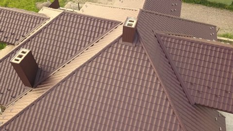 Aerial view of house roof structure covered with brown metal tile sheets.