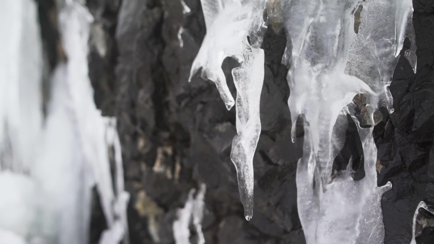 frozen waterfall on a rock is melting, close up