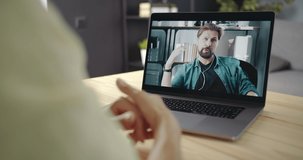 Business lady sitting at table, talking and gesturing during video chat with bearded partner. Two business person having video conference and online consultation at home.