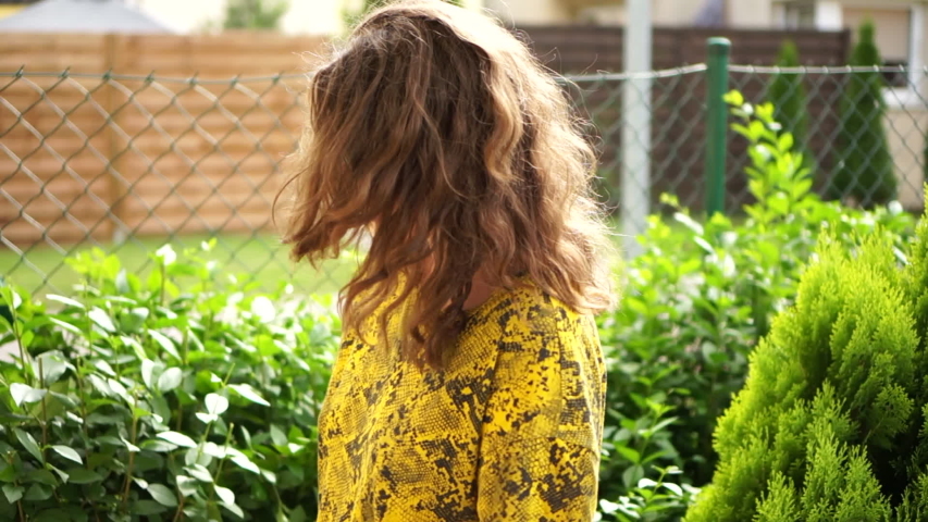 Close portrait of a lovely young woman in sunglasses in her garden. The girl holds clippers in her hands and laughs. Garden work, cutting bushes