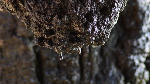 Water drops sliding through a rock in a cave