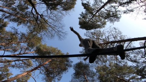 Man jumping and doing tricks on slackline in the forest in slow motion 