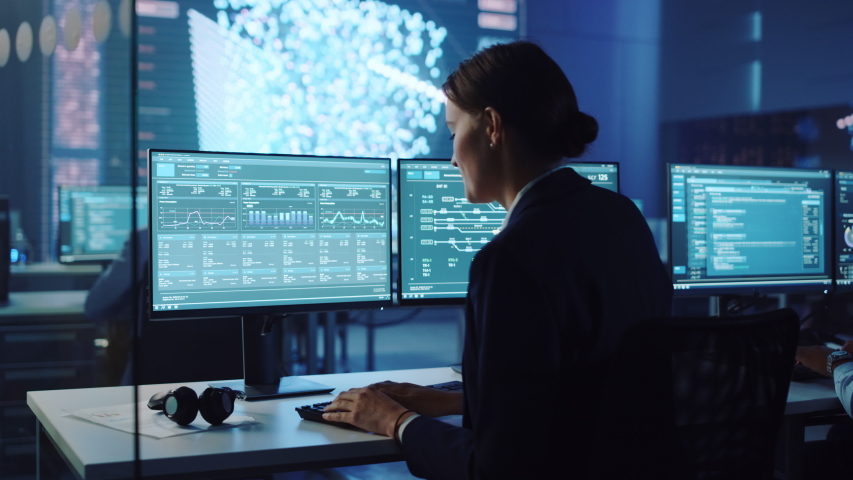 Confident Female Data Scientist Works on Personal Computer in Big Infrastructure Control and Monitoring Room with Neural Network. Woman Engineer in an Office Room with Colleagues. | Shutterstock HD Video #1055506751